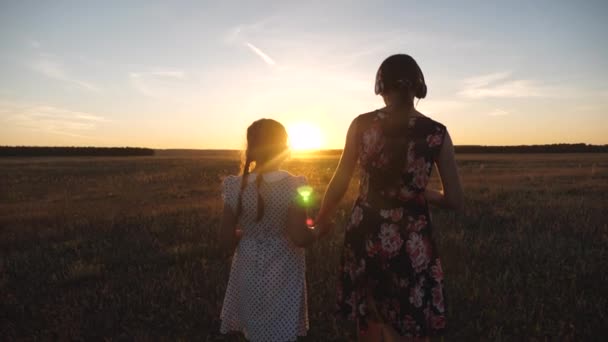 Las adolescentes felices van de excursión, escuchando música en los rayos de un hermoso atardecer. los niños van de la mano en el parque del amanecer. hermanas viajan y sueñan juntas . — Vídeos de Stock