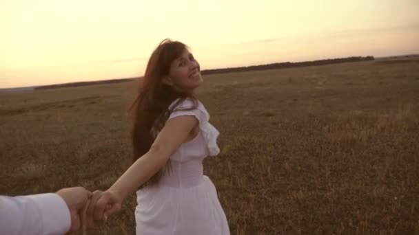 Girl runs across the field holding the hand of her beloved man and laughs. Slow motion. happy in love couple runs hand in hand. concept of a happy family. girl and man travel outside the city. — Stock Video