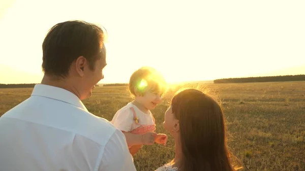 Pai com filhas descansando no parque. conceito de família feliz e infância. A família brinca com o bebê ao pôr-do-sol. Papai e mamãe andam com a filha nos braços ao pôr do sol . — Fotografia de Stock