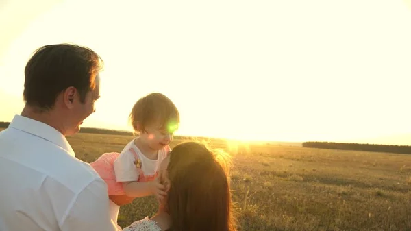 Fader med döttrar som vilar i parkera. begreppet lycklig familj och barndom. Familjen leker med barnet vid solnedgången. Pappa och mamma går med sin dotter i famnen vid solnedgången. — Stockfoto