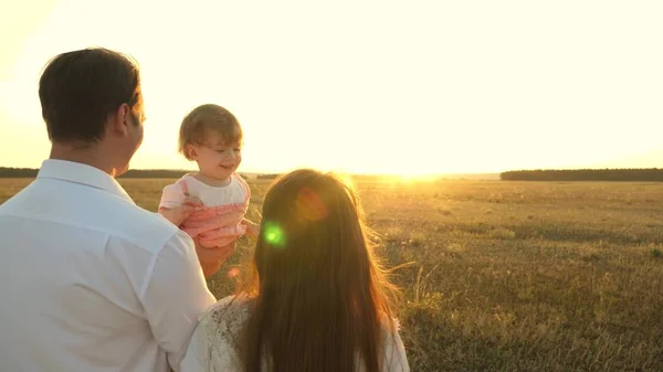 Ojciec z córkami spoczywających w parku. koncepcji szczęśliwej rodziny i dzieciństwa. Rodzina gra z dzieckiem o zachodzie słońca. Tata i Mama chodzą z córką w ramionach o zachodzie słońca. — Zdjęcie stockowe