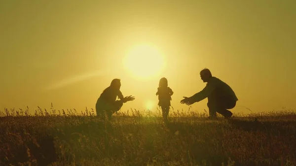 Мама и папа играют со своей дочерью на солнце. счастливый ребенок переходит от папы к маме. молодая семья в поле с ребенком 1 год. семейное счастье. красивый солнечный свет, закат . — стоковое фото