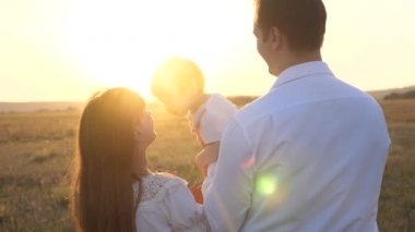 Babam ve annem kızı ile gün batımında kollarında yürüyebilir. gün batımında bir çocukla aile yürüyüşleri. Kız parkta dinlenmek ile baba. mutlu aile ve çocukluk konsepti.
