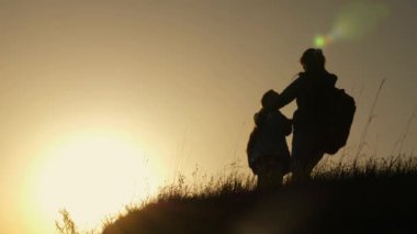 tatil seyahat ve dağda dans anne ve kızı. Dağın tepesinde, gün batımına bakarak yükseltilmiş elleri olan bir kadın. Hiker kız yetiştirmek onu el yukarı, kutluyor zafer ve zevk sahne.