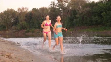 Kızlar sahilde kıyı boyunca kumda koşarlar su damlaları sıçrayıp gülerler. Yaz tatilinde mutlu ve özgür gençler gün batımında dinlenirler. Takım çalışması