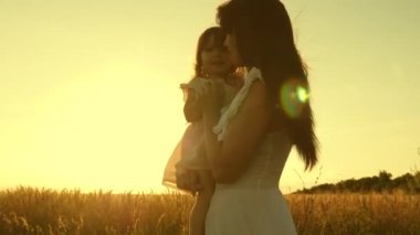 anne ve küçük kızı olgun buğday bir alanda oynuyorlar. anne buğday ile bir alanda bir çocuk ile yürür. mutlu aile seyahatleri. annemin kollarında bebek. mutlu aile kavramı.