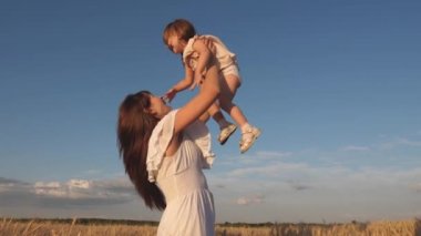 Annem mutlu bir kızı gökyüzüne fırlatıyor. olgun buğday bir alanda anne ve küçük bebek oyun. mutlu aile seyahatleri. annemin kollarında bebek. mutlu aile kavramı.