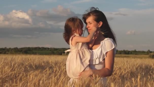 Mutter geht mit dem Baby auf das Feld und hält Stacheln mit Weizen in der Hand. Kleine Tochter küsst Mama auf einem Weizenfeld. glückliche Familienreisen. Baby in den Armen von Mama. Glückliches Familienkonzept. — Stockvideo