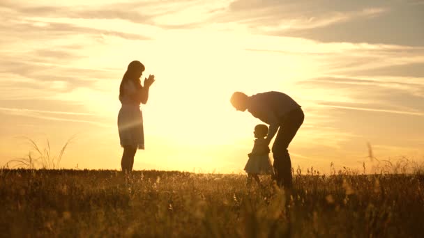 Máma s tátou si hráli s dítětem v parku při západu slunce, dítě dělá první schody. šťastná dcerka si hraje s matkou a otcem. šťastné dítě, hraní si s rodiči. — Stock video