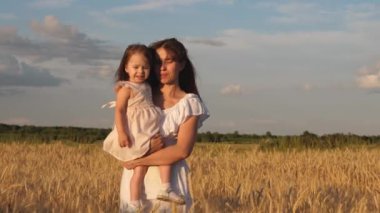 Anne ve küçük kızı olgun buğday tarlasında yürüyorlar. mutlu anne tarlada bebekle birlikte yürür. mutlu aile seyahatleri. annenin kollarında bebek dışarı çıkar. mutlu aile kavramı.