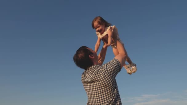 Táta vyhazuje šťastnou dceru na modrou oblohu. Otec a malé dítě si hrají, smějí se a objímají. Šťastná rodina cestuje. Dítě v náručí rodiče. Den volna. Koncept šťastné rodiny. — Stock video
