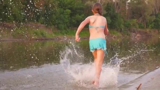 Happy Kids kör längs stranden. Flickor springa på sand längs stranden på stranden stänk vatten droppar och skrattar. Happy och gratis tonåringar på en sommarsemester har en paus i solnedgången. Lagarbete — Stockvideo