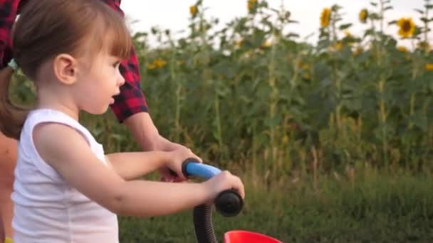 Mamá enseña a su hija a andar en bicicleta. Mamá juega con su hija pequeña. un niño pequeño aprende a andar en bicicleta. concepto de infancia feliz . — Vídeos de Stock