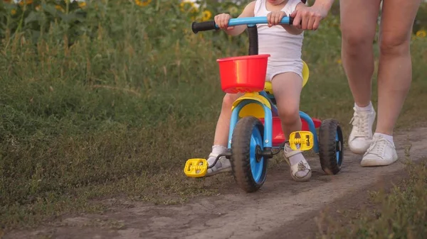 Mutter bringt Tochter Fahrradfahren bei. Nahaufnahme. Mutter spielt mit ihrer kleinen Tochter. ein kleines Kind lernt Fahrrad fahren. Konzept einer glücklichen Kindheit. — Stockfoto