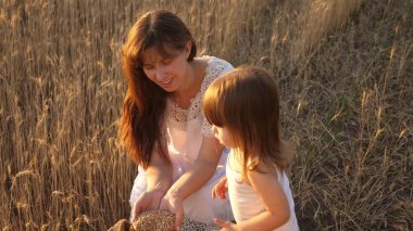 anne ve küçük çocuk bir buğday tarlasında torba içinde tahıl ile oynuyorlar. mutlu anne çiftçi küçük oğlu, tarladaki kızı yla oynuyor. Tarım kavramı.