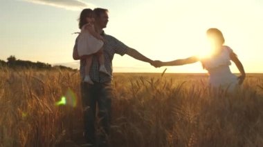 Yaz tarlasında yürüyen çocuklu Mutlu Genç Aile. Sağlıklı anne, baba ve küçük kız kız birlikte doğa zevk, açık havada. Yavaş çekim. 4k Uhd video 3840x2160