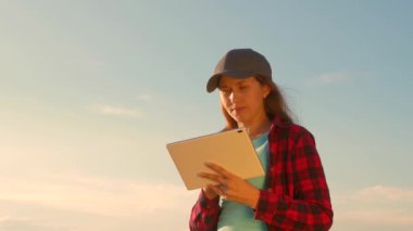 Çiftçi kız buğday tarlasında bir tabletle çalışıyor, tahıl mahsulünü planlıyor. tarım kavramı. Kadın agronomist tarlada buğday mahsulleri üzerinde çalışıyor. gelirini planlama alanında girişimci.