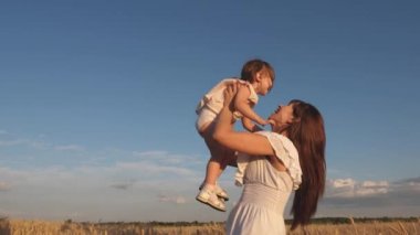 olgun buğday alanında anne ve küçük bebek oyun. mutlu aile seyahatleri. Annem mutlu bir kızı gökyüzüne fırlatıyor. annemin kollarında bebek. mutlu aile kavramı.