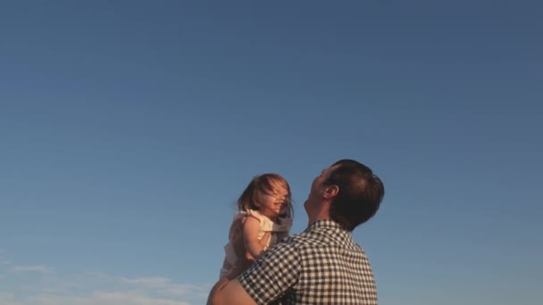 Отец и маленький ребенок играют, смеются и обнимаются вместе. Папа бросает счастливую дочь в голубое небо. Эппи семья путешествует. Ребенок на руках у родителей. Папин выходной. Концепция счастливой семьи — стоковое видео