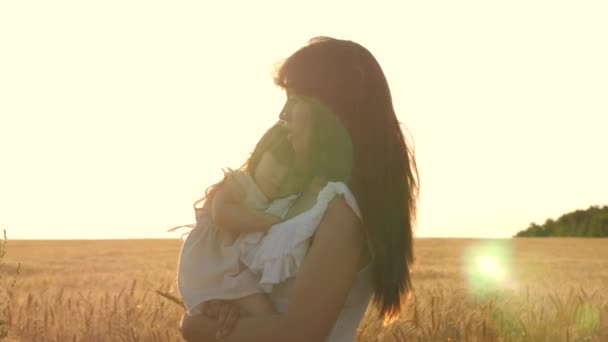 Happy Mama spacery z dzieckiem w ramionach w polu z pszenicy. Córka trzyma mamę przez klatkę piersiową. Rodzina podróżuje. — Wideo stockowe