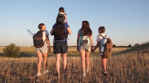 Bambini e padre e madre con zaini viaggiano attraverso la valle. Papà mamma con le figlie andare in campeggio. Famiglia di turisti in viaggio. lavoro di squadra di turisti. movimento verso la vittoria . — Video Stock