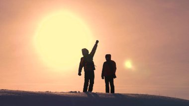 Turistler karlı tepenin üstüne gelir ve sarı bir günbatımı zemin karşı zafer sevinirler. gezginler başarı üstünde bir araya geldi. takım çalışması ve zafer. ekolojik turizm