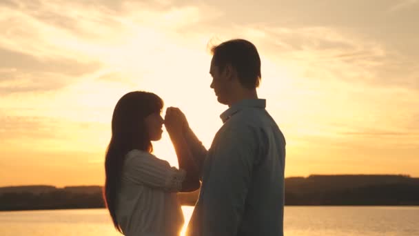 Liebender Mann und Frau tanzen in hellen Sonnenstrahlen auf dem Hintergrund des Sees. junges Paar tanzt bei Sonnenuntergang am Strand. Glücklicher Bursche und Mädchen Walzer am Abend im Sommerpark. — Stockvideo