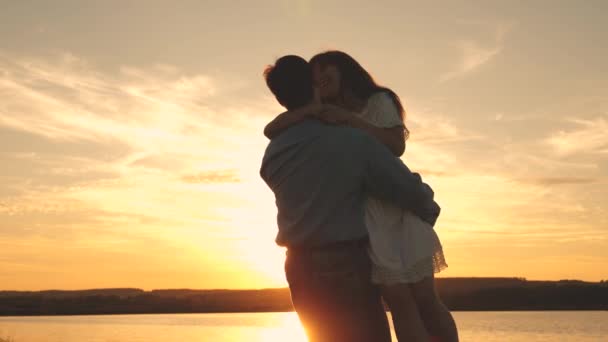 Happy guy and girl waltz in the evening in the summer park. Loving man and woman dance in bright rays of sun on the background of the lake. Young couple dancing at sunset on beach. — Stock Video