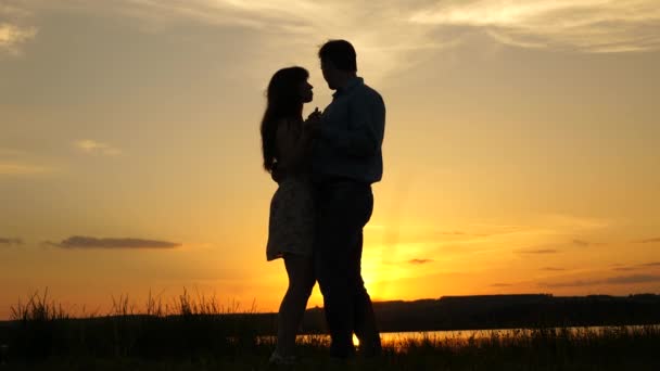 Молодая пара танцует на закате на пляже. Любящий мужчина и женщина танцуют в ярких лучах солнца на фоне озера. Счастливый парень и девушка вальсируют вечером в летнем парке . — стоковое видео