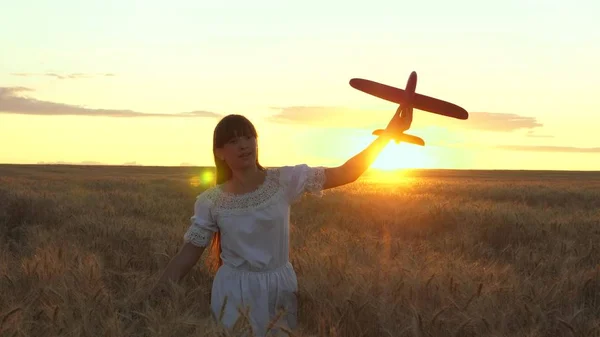 Ragazza felice corre con un aeroplano giocattolo su un campo di fiori. i bambini giocano aereo giocattolo. adolescente sogna di volare e diventare un pilota. la ragazza vuole diventare un pilota e astronauta . — Foto Stock