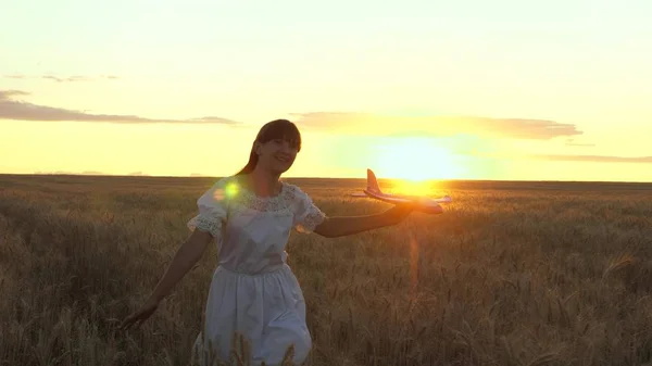 Menina feliz corre com um avião de brinquedo em um campo de flores. As crianças brincam de avião de brinquedo. adolescente sonha em voar e se tornar um piloto. a menina quer se tornar um piloto e astronauta . — Fotografia de Stock