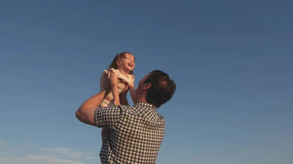 Papa geeft een gelukkige dochter over aan de blauwe lucht. Vader en kind spelen, lachen en knuffelen samen. Gelukkige familie reist. Baby in de armen van de ouder. Pap vrije dag. Het concept van een gelukkig gezin. — Stockfoto
