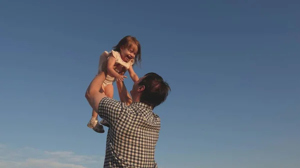 O pai vomita uma filha feliz no céu azul. Pai e criança brincam, riem e abraçam juntos. Feliz viagem de família. Bebê nos braços dos pais. Dia de folga do pai. O conceito de uma família feliz. — Fotografia de Stock