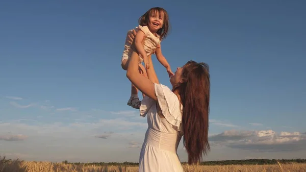 Mère et petit bébé jouent sur le terrain de blé mûr. famille heureuse voyage. Maman vomit une fille heureuse dans le ciel. bébé dans les bras de maman. concept de famille heureuse . — Photo
