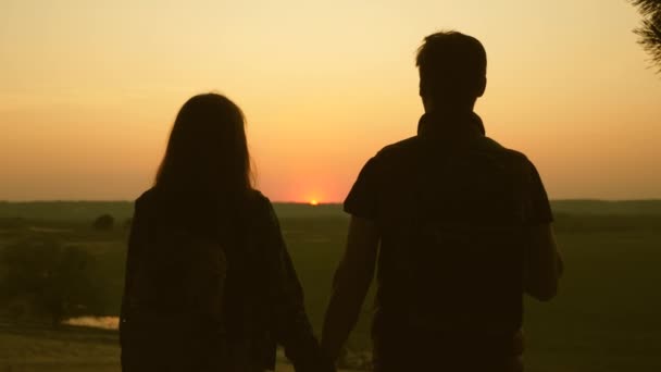 Viajantes Homem e mulher levantam as mãos para o sol e desfrutam do pôr do sol. Viajantes de trabalho em equipe com mochilas. Família de turistas de férias. viagens desfrutar da paisagem ao pôr do sol. Caminhante. Movimento lento . — Vídeo de Stock