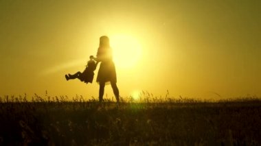 Annem kızıyla gün ışığında oynuyor. anne-babalar küçük kızı ile oynamak. mutlu çocuk gün batımında parkta annesi ile yürür. 1 yaşında bir bebek ile alanında aile. aile mutluluğu kavramı.