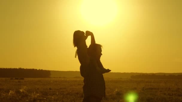 Mała córka jedzie z tatą na ramionach w parku. Tata nosi ukochanego dziecka na ramionach chodzenie po polu o zachodzie słońca. Dziecko z rodzicem spacery wieczorem o zachodzie słońca. Zwolnionym. — Wideo stockowe