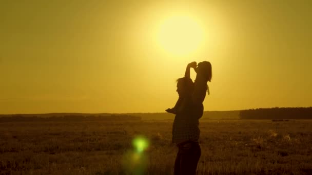 Dziecko z rodzicem spacery wieczorem o zachodzie słońca. Tata nosi ukochanego dziecka na ramionach chodzenie po polu o zachodzie słońca. mała córka jedzie z tatą na ramionach w parku. Zwolnionym. — Wideo stockowe