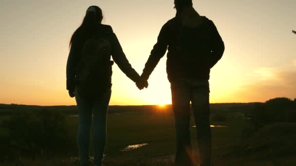 Resenärer man och kvinna hålla varandras händer och njuta av landskapet vid solnedgången. Älskare resenärer reser med ryggsäckar. Hiker flicka. Lycklig familj av turister på semester resor. Romantiskt förhållande — Stockvideo