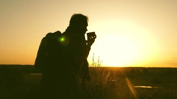 Viajero bebe té caliente y mira atardecer. descansar después de alcanzar la meta. turista solitario sentado en la cima de la colina bebiendo café en termos. concepto de libertad y sueños. mundo sin fronteras —  Fotos de Stock