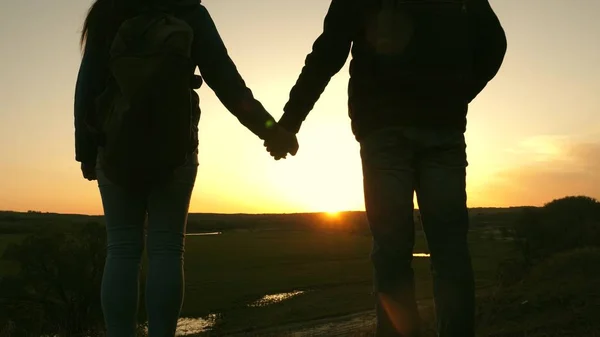 Travelers man and woman hold each others hands and enjoy the scenery at sunset. Lovers travelers travel with backpacks. Hiker Girl. Happy family of tourists on vacation travels. Romantic relationship