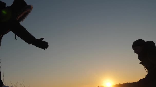 Männer helfen einander, den Gipfel des hohen schneebedeckten Berges zu bezwingen, indem sie sich an den Händen halten und sich bei Sonnenuntergang nach oben strecken. kalte natürliche Bedingungen auf Reisen. Extremwanderungen für Mutige — Stockvideo