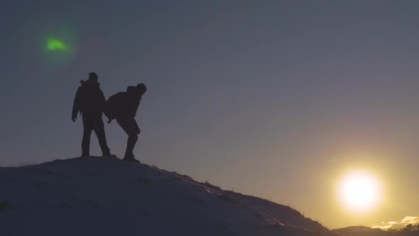 Viajantes descem de uma montanha nevada alta, à procura de aventura na luz do sol brilhante no inverno. conceito de turistas conquistando a montanha. alpinistas de trabalho em equipe amigos nas montanhas — Vídeo de Stock