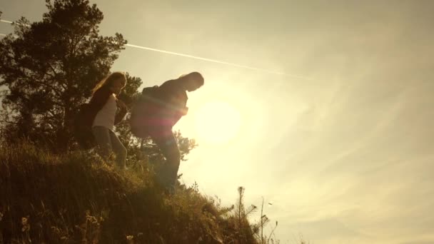 Podróżny dziewcząt zejć z góry. Dziewczyna Hiker. Rodzina turystów podróżujących o zachodzie słońca. siostry z plecakami podróżują w dół wzgórza w słońcu. Praca zespołowa turystów — Wideo stockowe