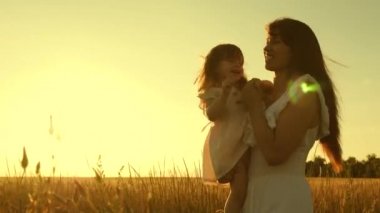 Anne ve kızı gün batımında olgun buğday ile bir alanda etrafında oyalanmak vardır. Mutlu annelik. Küçük bir çocuk annesinin kollarında kahkahalarla doludur..