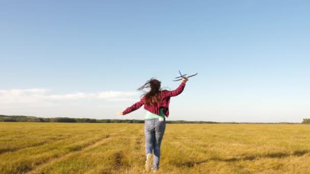 Teenager dreams of flying and becoming pilot. Happy girl runs with a toy airplane on a field in the sunset light. children play toy airplane. the girl wants to become pilot and astronaut. Slow motion — Stock Video