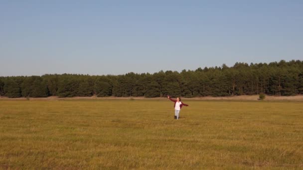 Chica quiere convertirse en piloto y astronauta. adolescente sueña con volar y convertirse en piloto. Chica feliz corre con un avión de juguete en un campo en la luz del atardecer. niños juegan juguete avión. Movimiento lento — Vídeo de stock