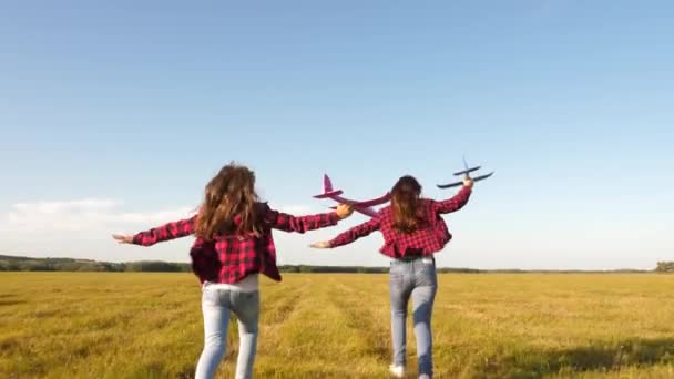 Діти грають у іграшковий літак. Підлітки хочуть стати пілотом і астронавтом. Щасливі дівчата бігають з іграшковим літаком на заході сонця на полі. концепція щасливого дитинства. Дівчата мріють літати і стати пілотом . — стокове відео