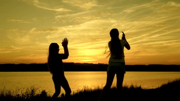 Fête au bord du lac, les enfants dansent. filles heureuses dansant sur la plage. belles filles s'amusent à écouter de la musique. les sœurs dansent. adolescence copines vacances disco . — Video