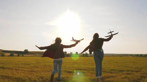 Kinder spielen Spielzeugflugzeug. Teenager wollen Pilot und Astronaut werden. Glückliche Mädchen rennen bei Sonnenuntergang mit einem Spielzeugflugzeug über das Feld. Konzept einer glücklichen Kindheit. Mädchen träumen vom Fliegen und Pilot werden. — Stockfoto